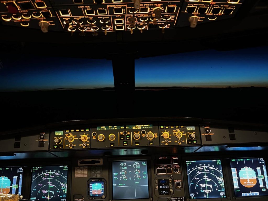 Airbus A320 cockpit lit with ECAM warnings during night flight