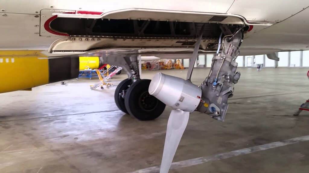 Airbus A320 Ram Air Turbine (RAT) deployed mid-flight with detailed view of the spinning turbine and cloudy sky background