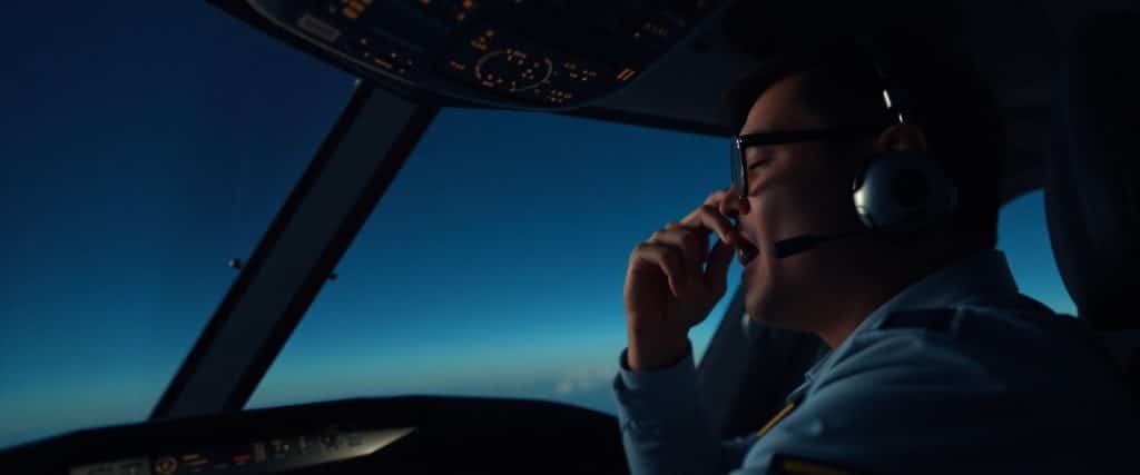 Tired airline pilot experiencing fatigue in a dimly lit cockpit
