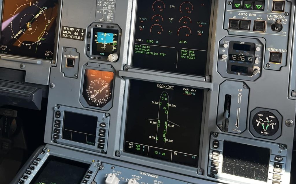 Airbus A320 flight deck showing overhead cabin pressurization panel and ECAM system display